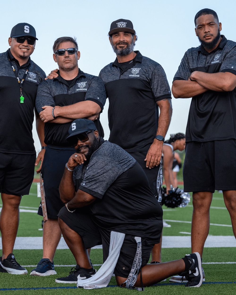 Chris Reid's team standing with a high school coaching staff on the field